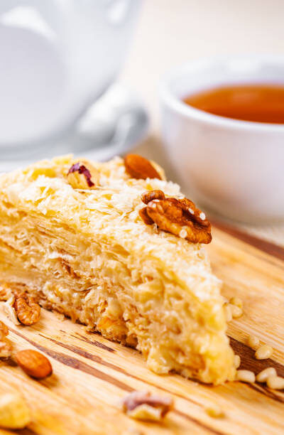 Napoleon cake with different nuts on wooden board